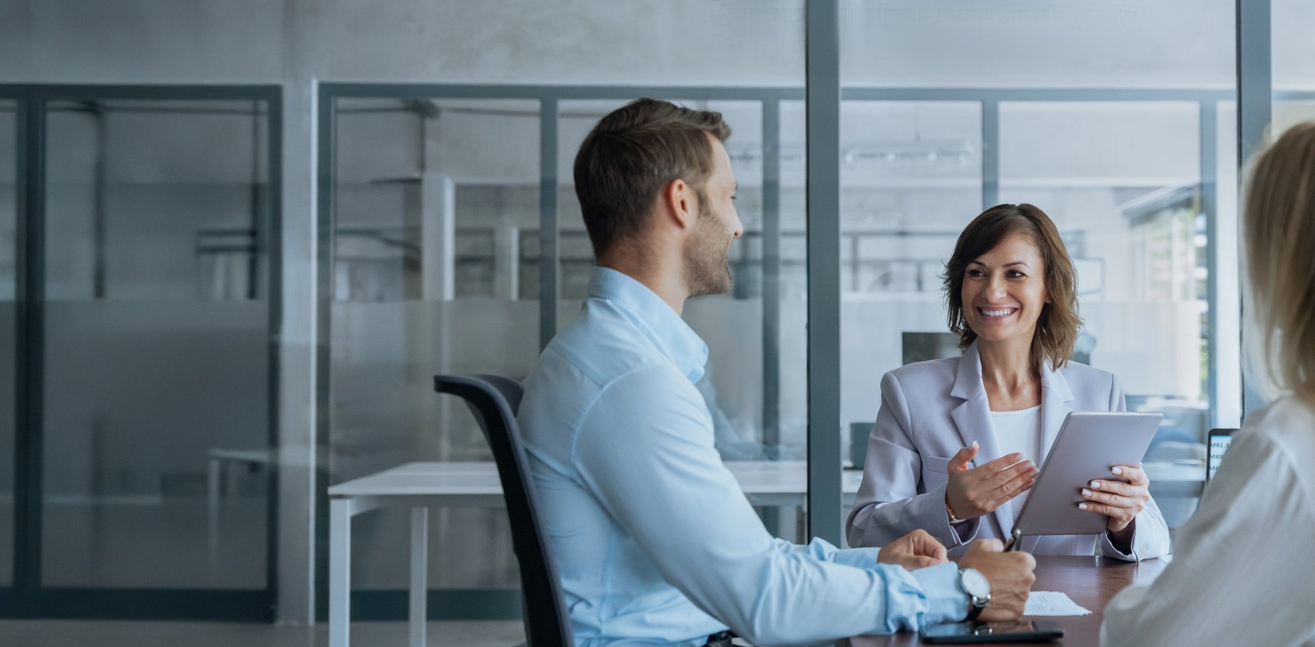Senior advisor discussing strategy with colleagues around a tablet in a modern office